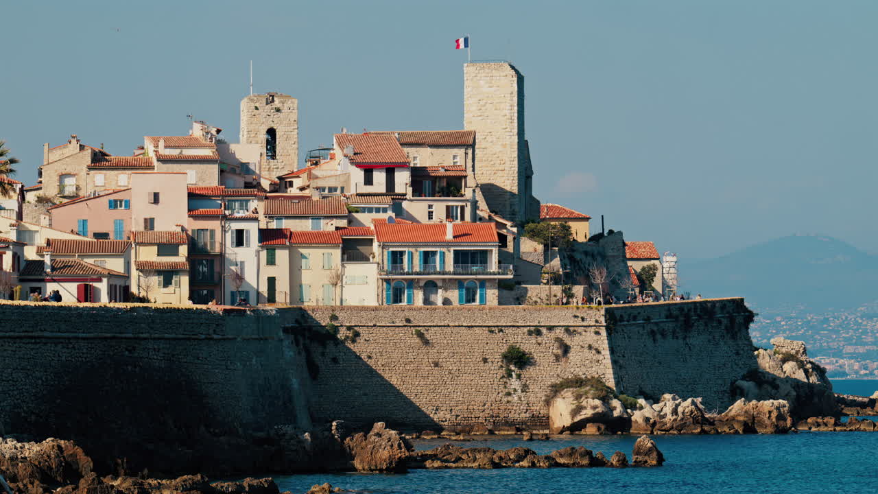 Vista distante di persone che camminano sulla costa di Antibes, Francia
