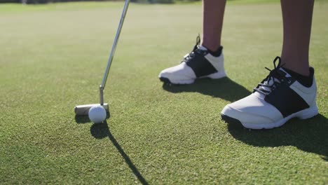 caucasian female golf player taking shot from bunker standing on golf field