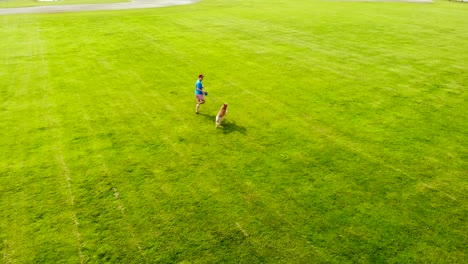 Hombre-Corriendo-Libremente-Por-El-Campo-De-Hierba-Con-Perro