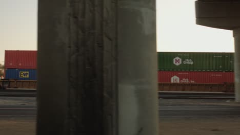 pase de tren de carga bajo el puente de la autopista a través del tráfico