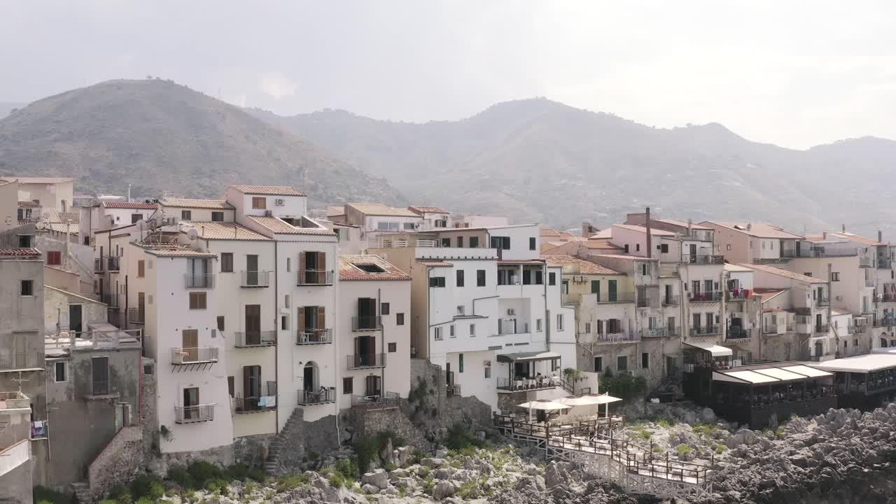 pueblo costero italiano con montañas en el fondo