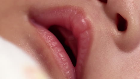 close-up shot of the gaping mouth of a newborn child, showing its pinkish lips including its nostrils.