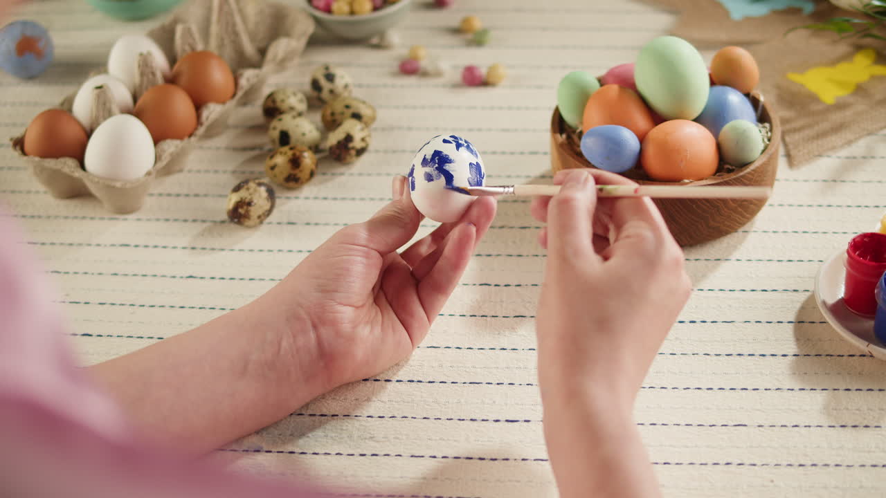 Close-up of Hands Decorating an Easter Egg with Blue Paint