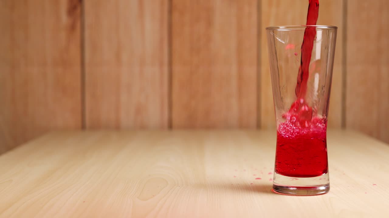 Bevanda rossa versata in un bicchiere trasparente