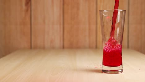 red drink being poured into a clear glass