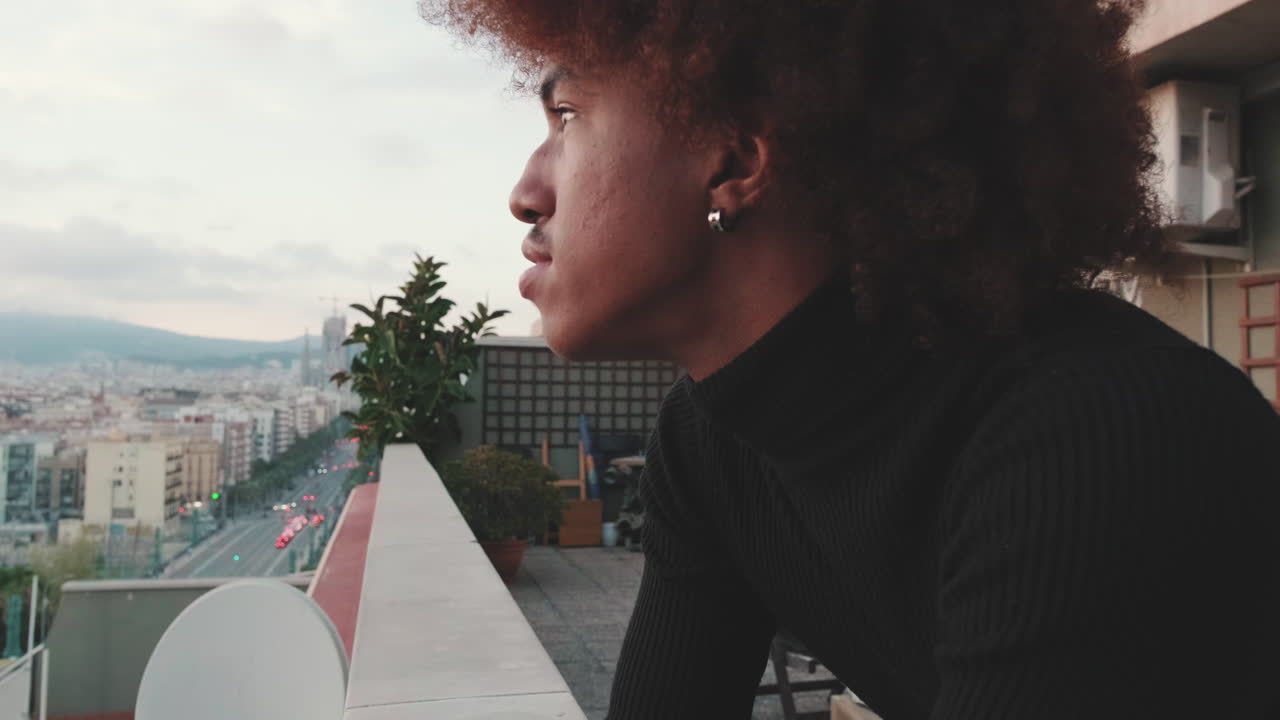 Man on a rooftop balcony in a city