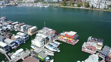 a colorful and vibrant pass over house boats in the marina as the camera reveals the large city in proximity