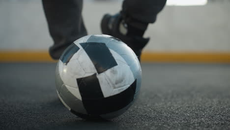 vista de cerca de la pierna de una deportista que demuestra giros precisos del tobillo con la pierna izquierda y derecha mientras controla la pelota de fútbol en la arena deportiva contra un fondo de pared pintado de amarillo