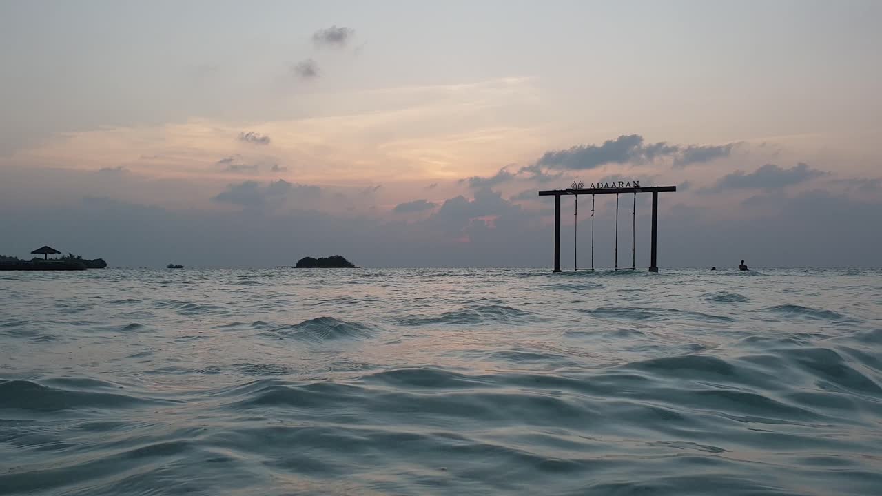 Low angle of swing in middle of ocean in Maldives at dusk. Panning