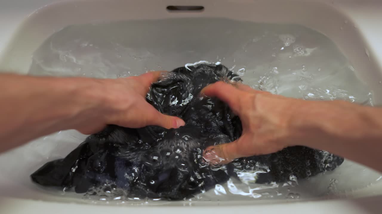 욕실 세면대에서 셔츠를 손으로 씻는 남자