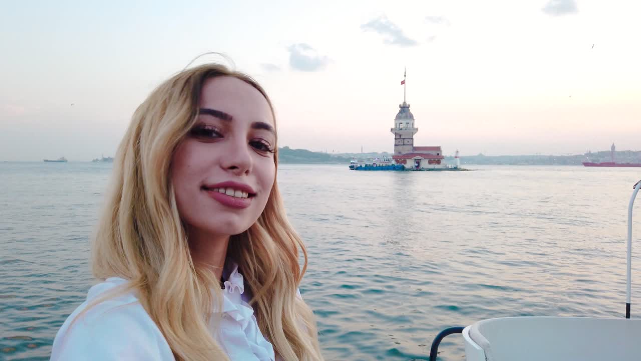 красивая девушка наслаждается видом на закат на босфор с видом на девичью башню на заднем плане в стамбуле