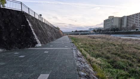 person biking on riverside path in kyoto