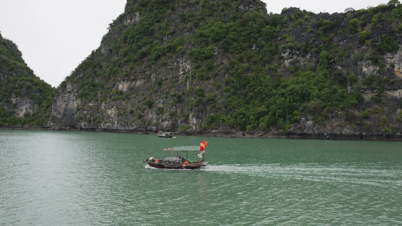 베트남의 석회암 숲 산맥을 배경으로 하롱 만에서 전통적인 단일 보트 크루즈