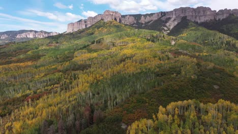 coloridas laderas cubiertas de álamos verdes y amarillos y picos de montañas rocosas vistos en un hermoso cielo azul día de otoño en colorado cerca del paso de owl creek