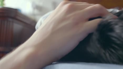 a cute black dog with brown eyes about to fall asleep in bed, receives petting from its owner