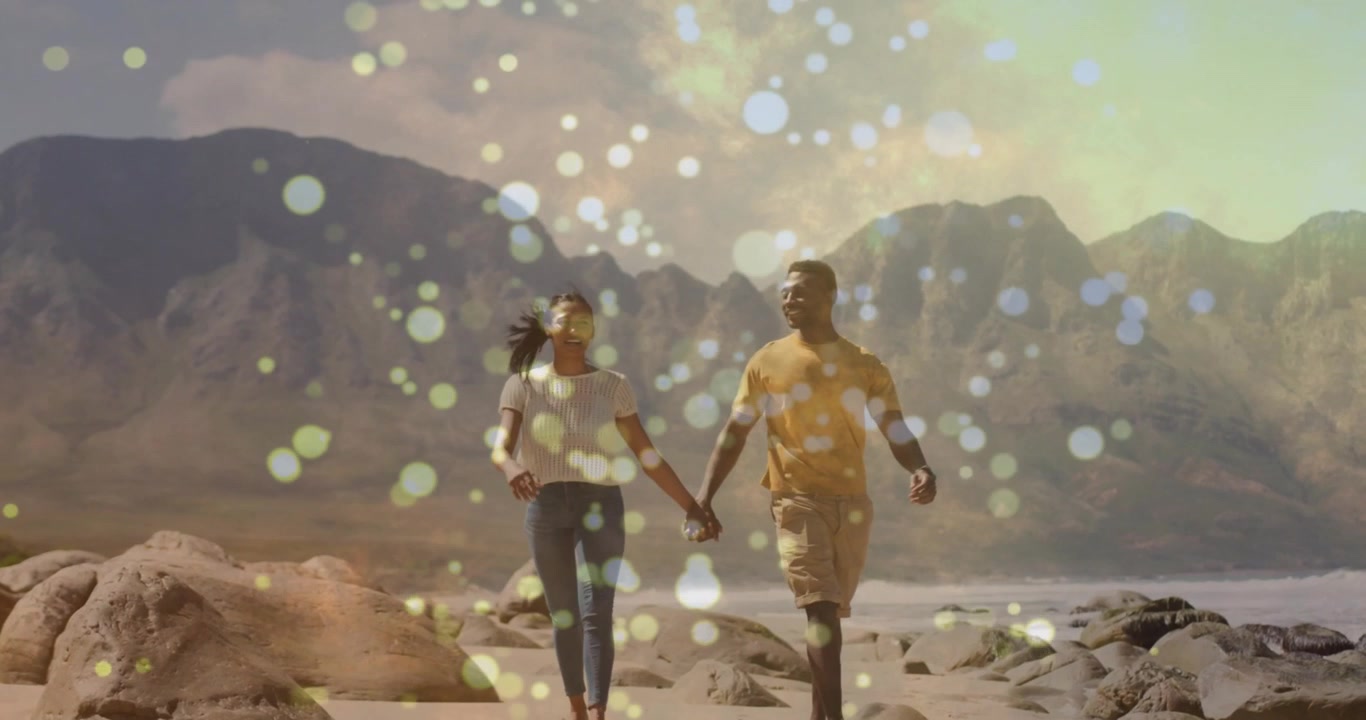 Coppia che cammina sulla spiaggia, mano nella mano, verso la fotocamera, per marketing di viaggio con effetto bokeh.