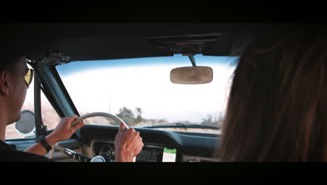 pareja joven conduciendo un coche viejo, sobre el hombro vista de cerca