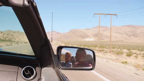 two men in convertible car driving along road shot on r3d