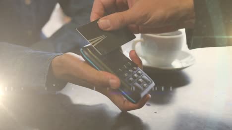 animation of light spots over hands of caucasian man paying with credit card