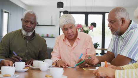 happy senior diverse people drinking tea and playing bingo at retirement home