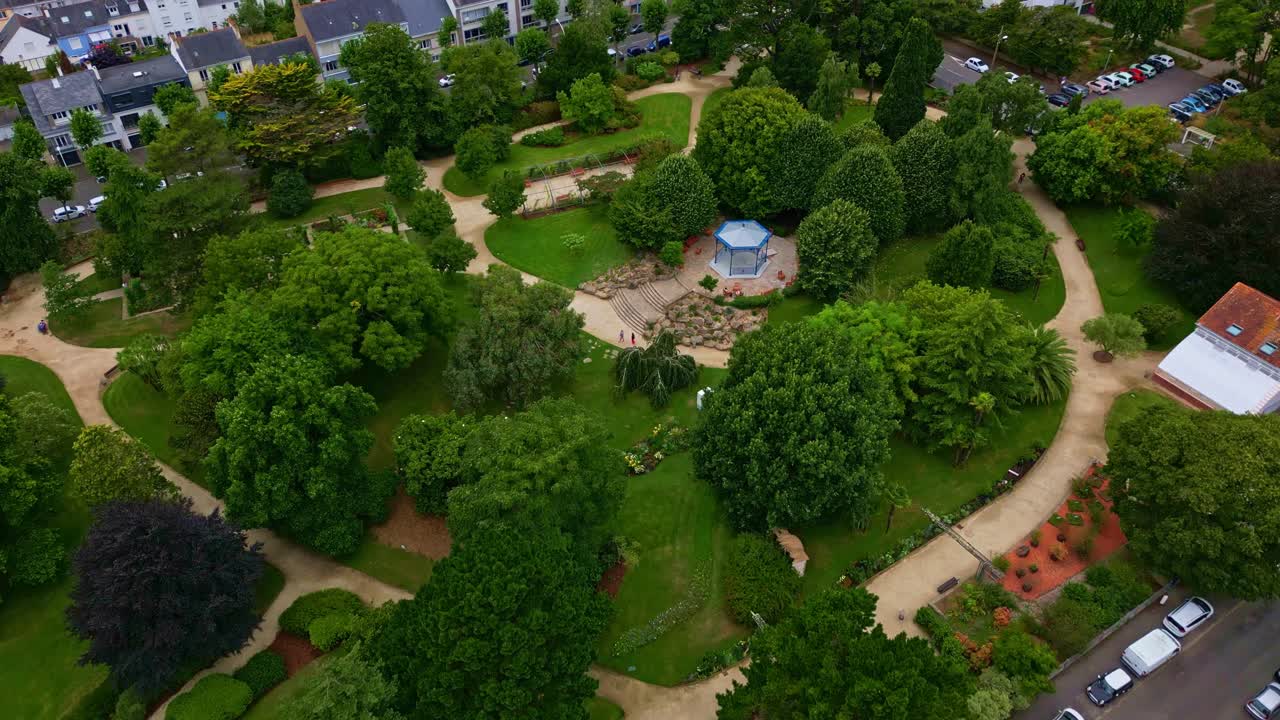 Jardin des Plantes public park in Saint-Nazaire, lush green trees and central kiosk, France. Aerial top-down forward