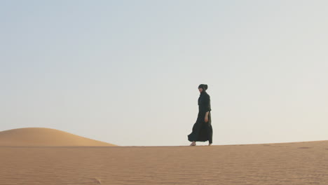 muslim woman in hijab walking barefoot in the desert