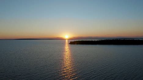 drohne bewegt sich über einem herrlichen see im norden kanadas auf die untergehende sonne zu