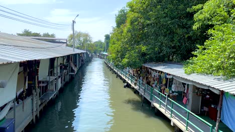 a tranquil canal scene at khlong lat mayom floating market in bangkok, showcasing vibrant greenery and traditional market stalls