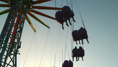 Tiefwinkelansicht-Einer-Fairen-Kettenschaukelfahrt-In-Der-Abenddämmerung,-Die-Sich-Um-Menschen-Dreht,-Statisch