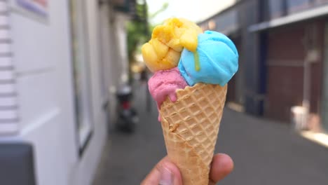 a close-up shot of a delicious ice cream cone with yellow, blue, and pink ice cream scoops.