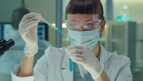 female lab scientist pouring blue chemical in test tube