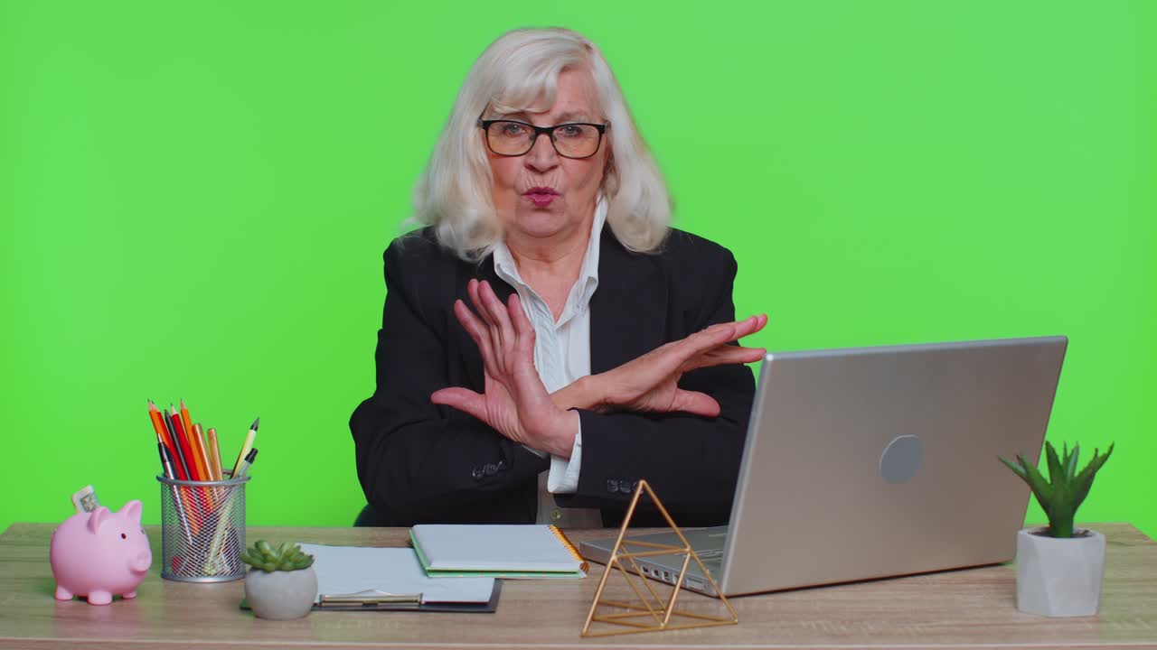 Senior businesswoman say no hold palm hand in stop gesture, warning of prohibited access danger