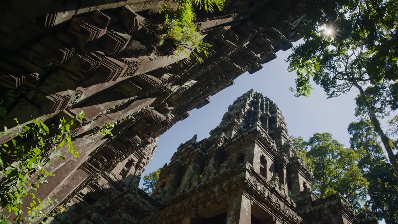 Low-angle video shot of ancient temple ruins, capturing intricate stone carvings and lush greenery