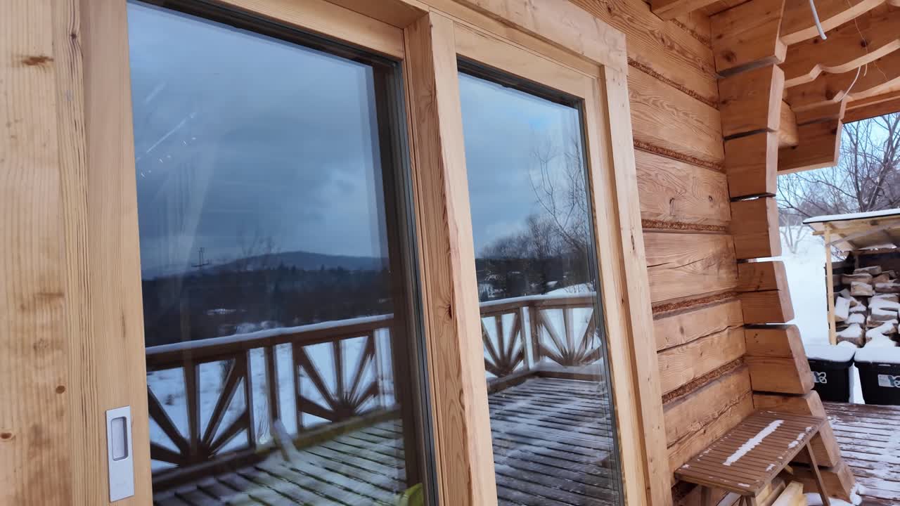 Lumisen hirsihuvilan parvekkeella sulkeutuva puinen liukuovi