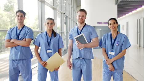 medical interns wearing scrubs walk towards camera in busy hospital