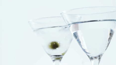 animation of red specks moving over cocktail glasses with olives on white background