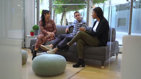 multiethnic colleagues sitting on couch in office