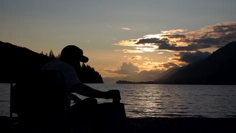 hermosa puesta de sol en un lago con un hombre tomando un trago de una lata