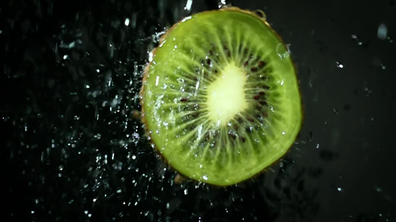 kiwi com salpicos de água clara em fundo preto. super câmara lenta.