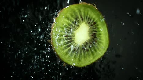 kiwi con salpicaduras de agua clara sobre un fondo negro. súper cámara lenta.