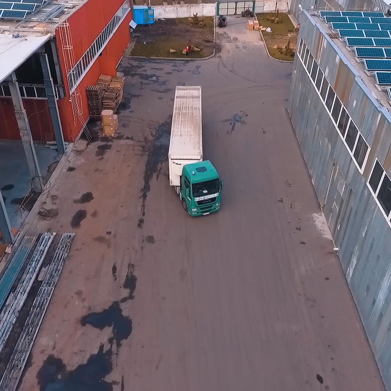 Solar photovoltaic panels on roof. White truck moving among industrial buildings with sunny batteries on roofs. Aerial view.