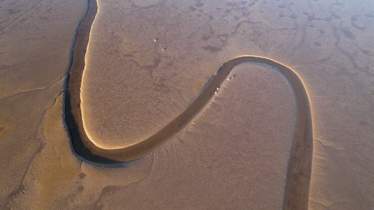 Aerial top down, river channel curving surrounded by dry sandy land