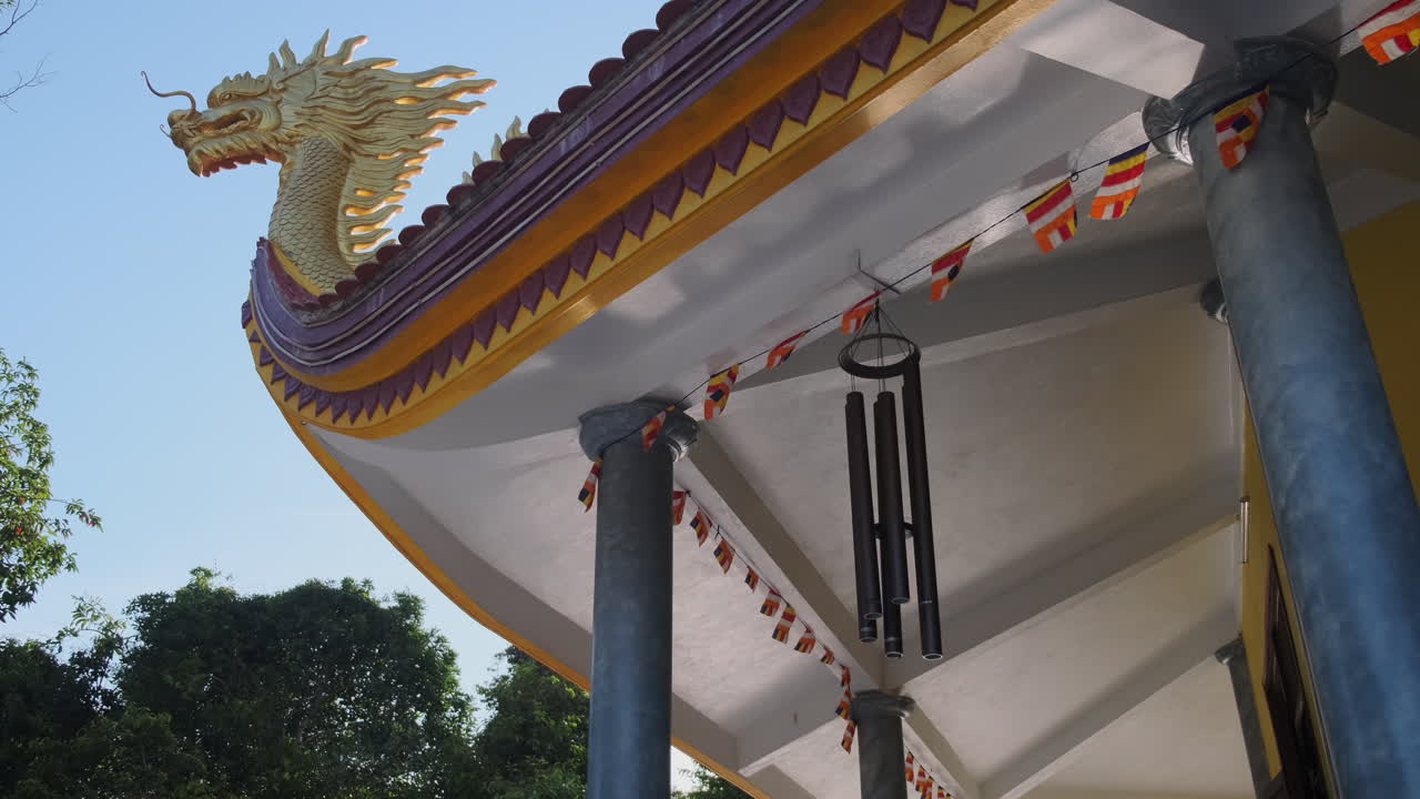 cabeza de dragón y campanas de viento en el techo de un templo
