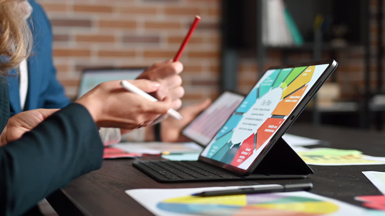 A man and a woman analysing a chart on a tablet at a table in an office
