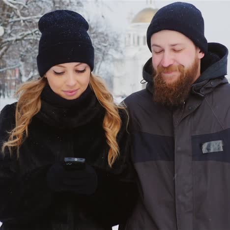 young couple walks in park using smartphone