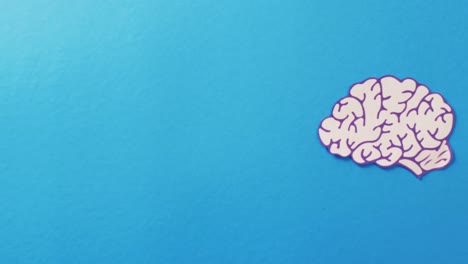 video of white and purple paper brain on blue background with copy space