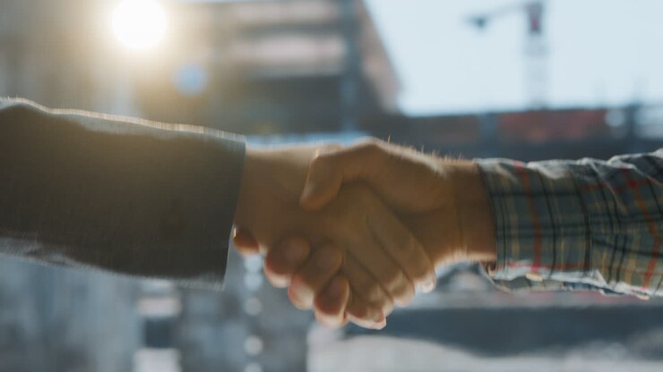 Professional Handshake with Sun Flare at a Construction Site