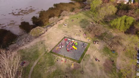 fantasma en órbita aérea de niños divirtiéndose en el patio de recreo en el parque junto al río en sumset