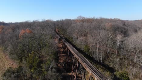 aerial shot pulling away from the end of the pope lick railroad trestle where the tracks curve into the forest in louisville kentucky