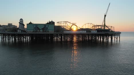 brighton pier uk and at sunrise, with sun shinning through funfair